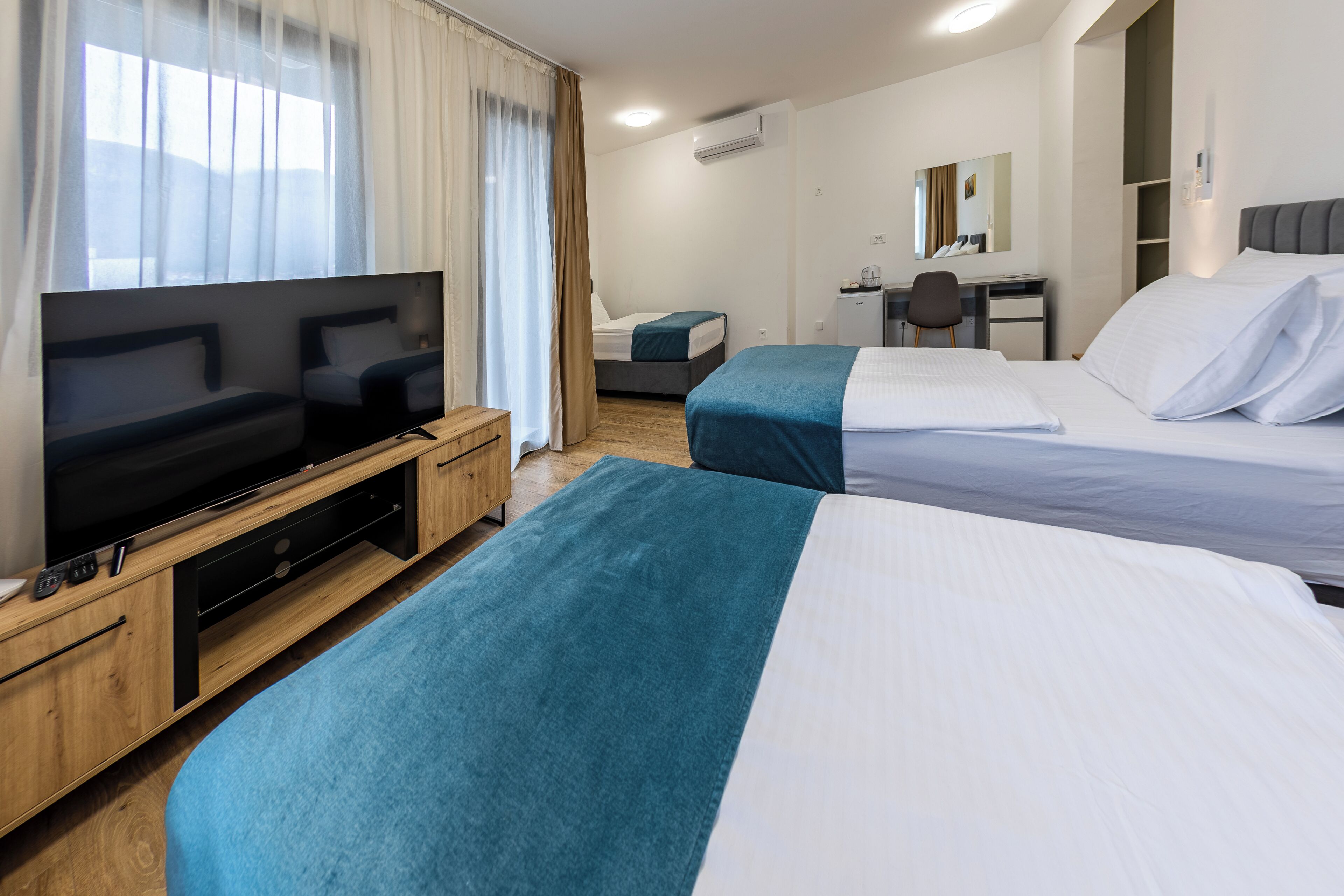 A hotel room with two beds, a TV, a desk, and a chair.