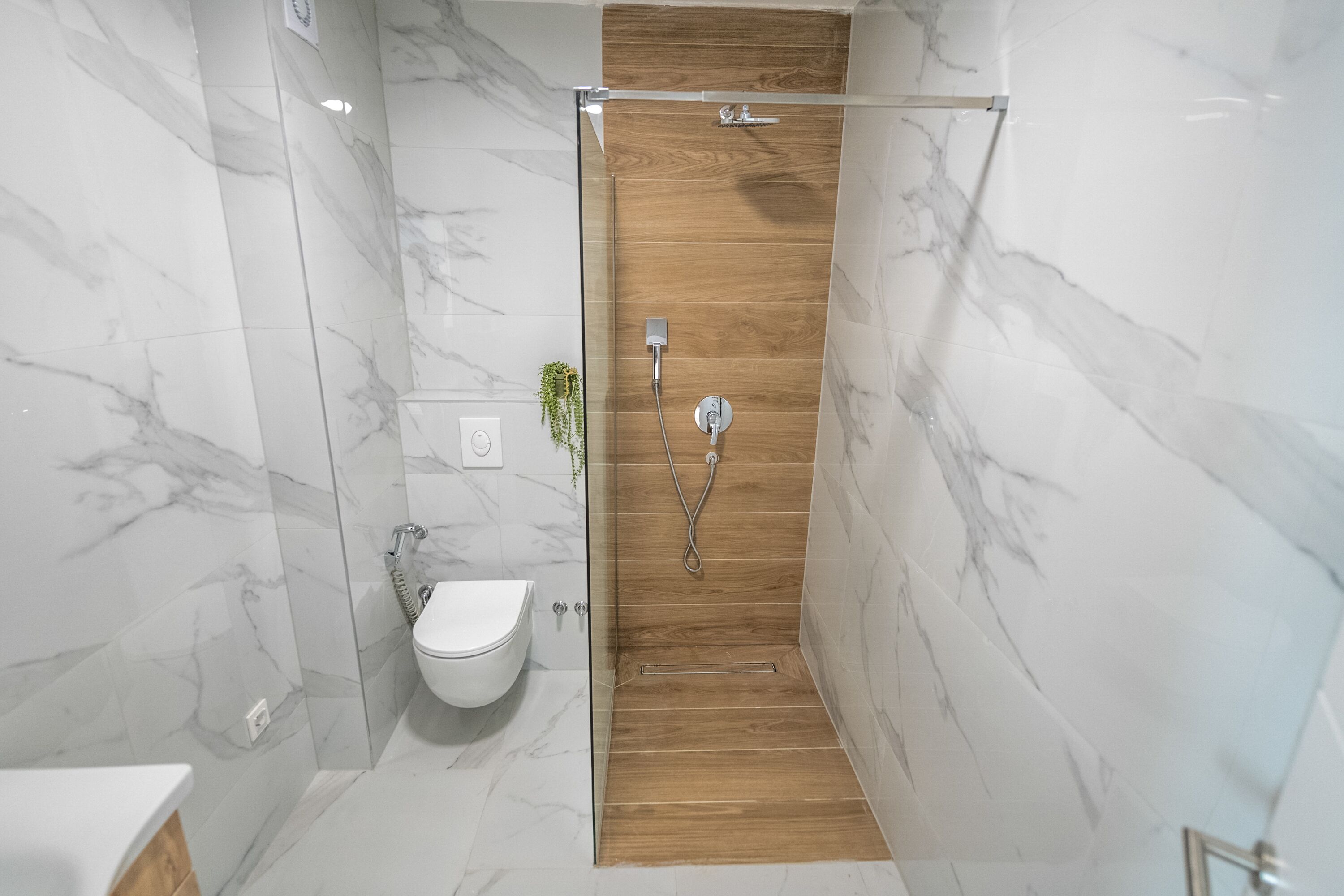 Une salle de bain moderne avec une douche à parois de verre, un meuble-lavabo en bois et un sol carrelé en marbre.