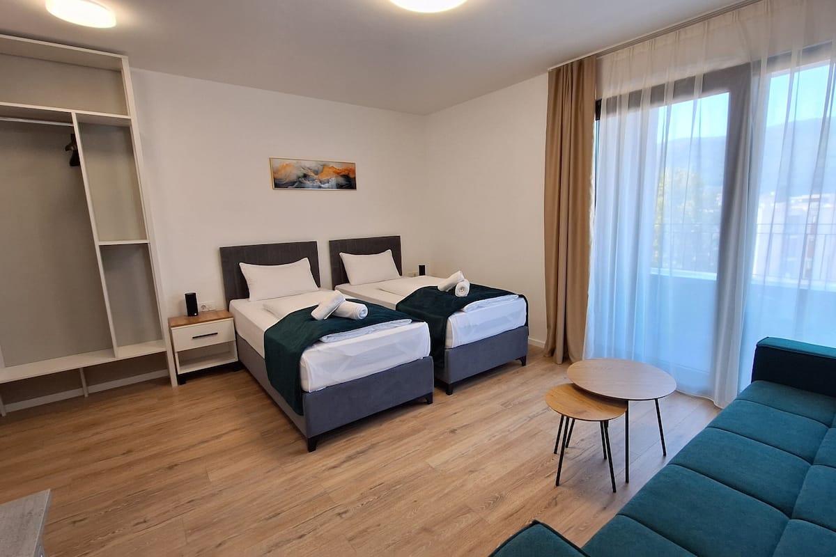 A hotel room with two beds, a sofa, a small table, and a closet.