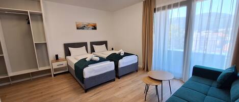 Una habitación de hotel con dos camas, un sofá, una mesita y un armario.