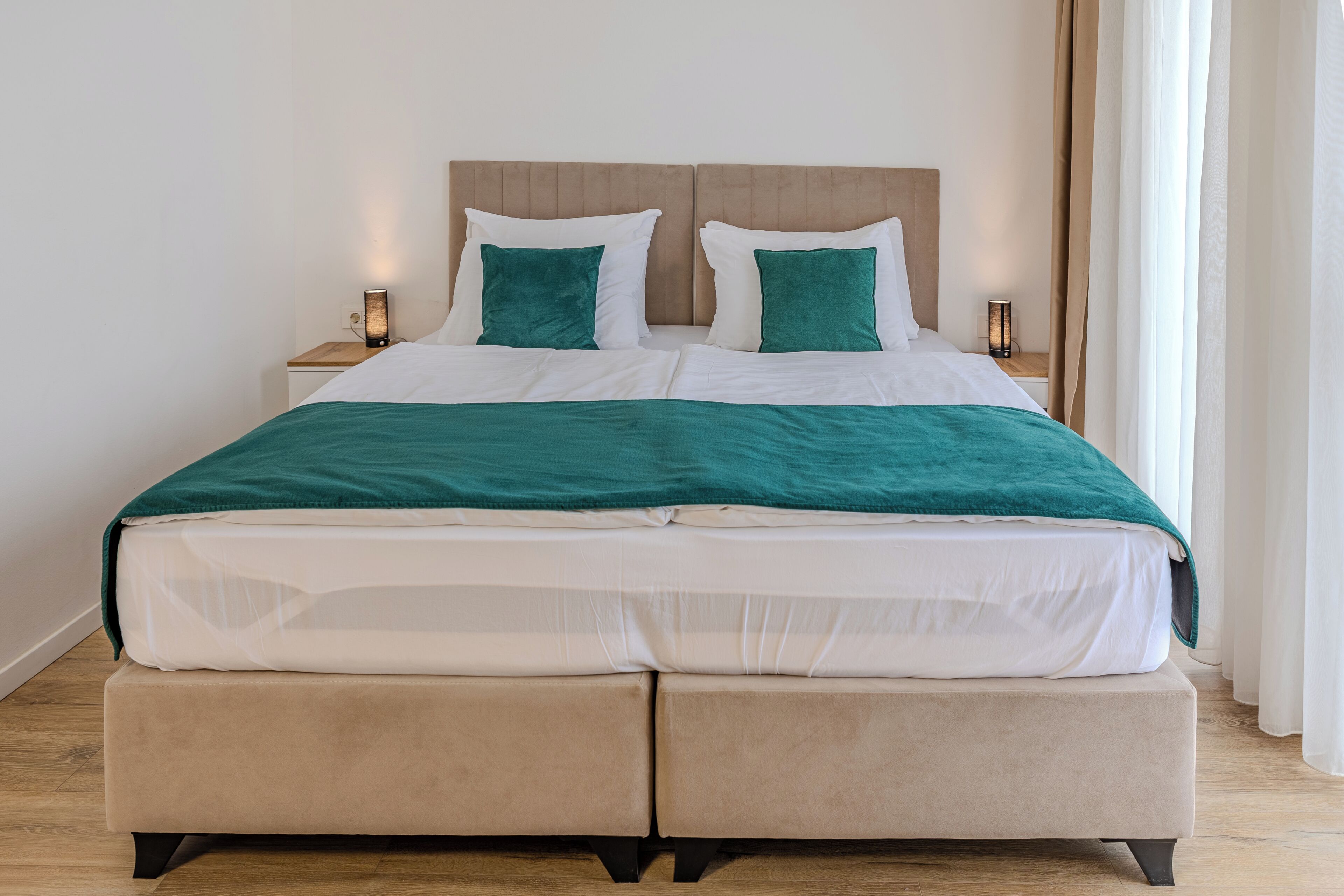 Un letto matrimoniale con una testiera in legno, due comodini con lampade e una coperta verde.