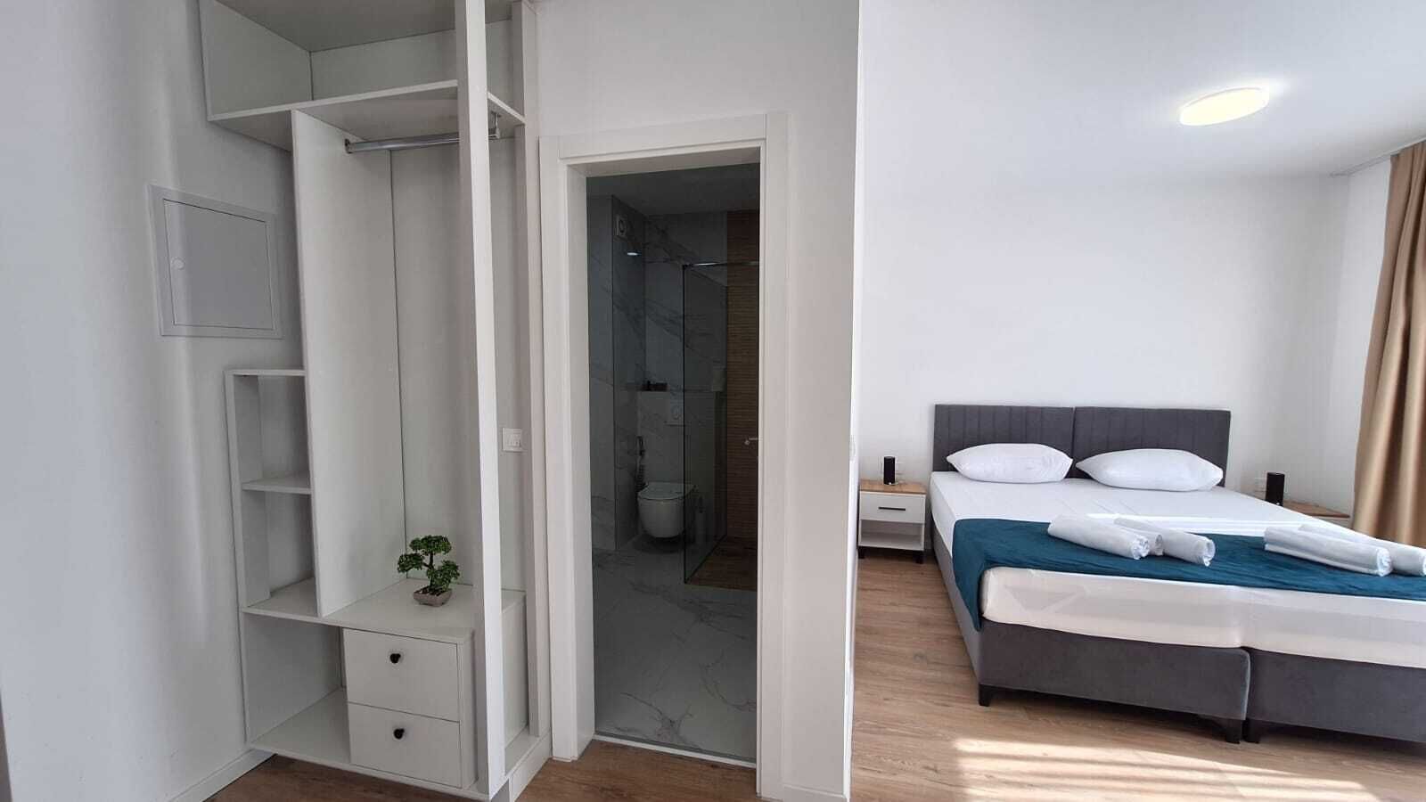 A modern hotel room with a bed, bedside table, and a walk-in closet.