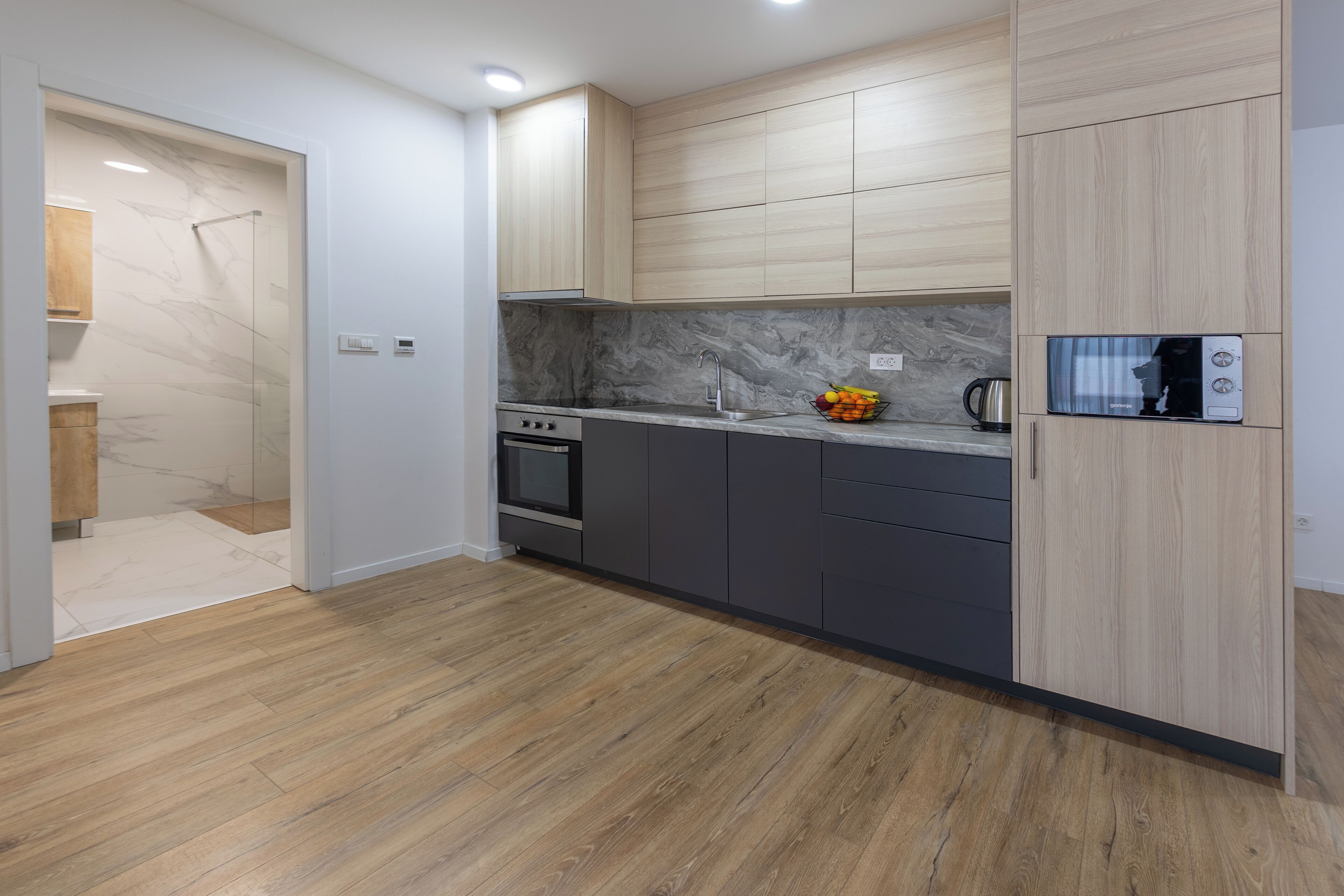 A modern kitchen with wooden cabinets, a built-in oven, and a microwave.