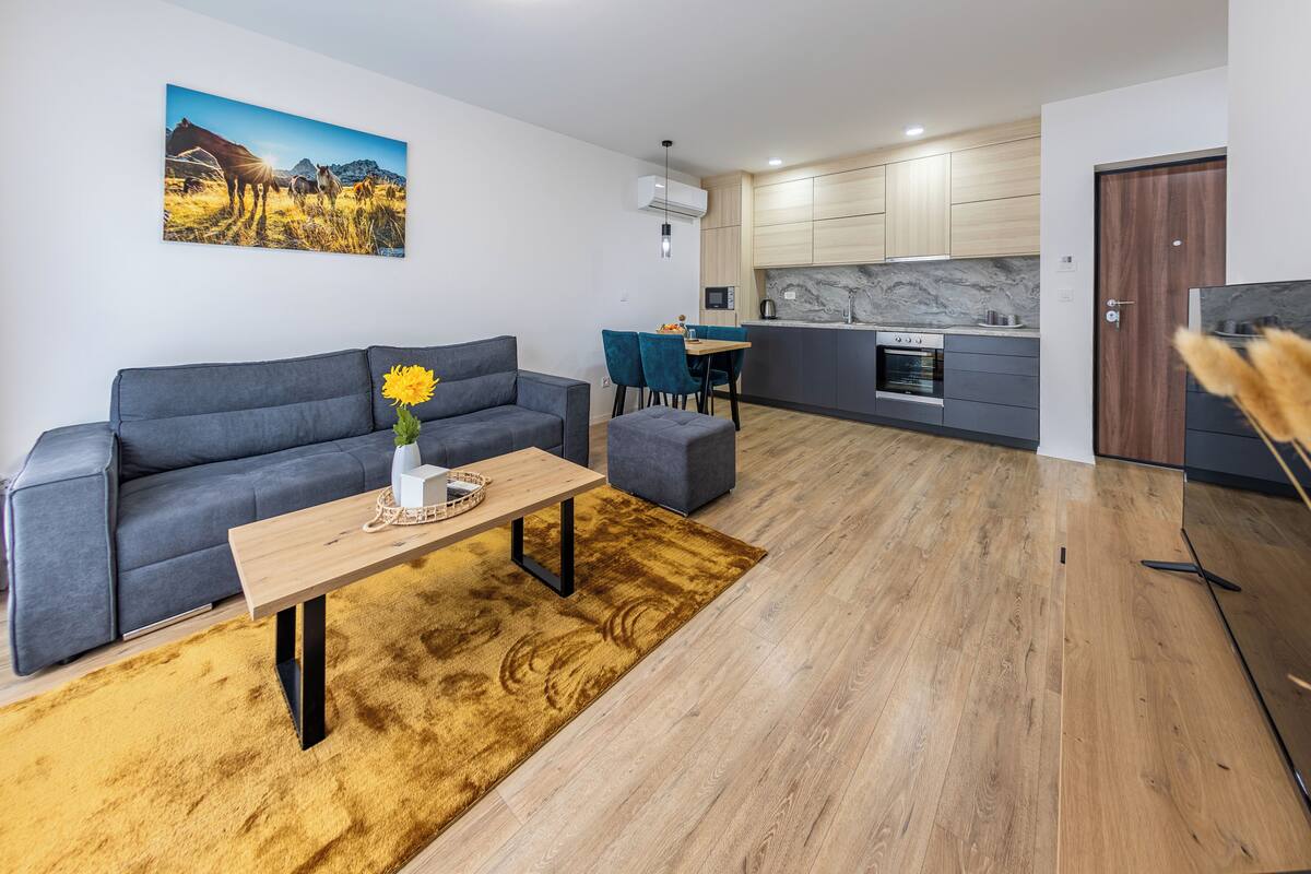 A modern living room with a sofa, coffee table, and a painting of horses.