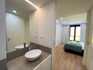 Ein modernes Badezimmer mit einem großen Spiegel, einem weißen Waschbecken und Holzboden.