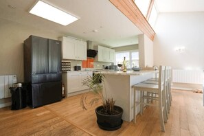 A modern kitchen with a central island, white cabinets, and a black refrigerator.