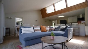 A modern living room with a sectional sofa, a coffee table, and a dining area in the background. - Carew, Bantham Beach in S. Devon (Bantham)