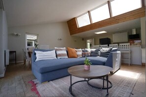 A modern living room with a sectional sofa, a coffee table, and a dining area in the background. - Carew, Bantham Beach in S. Devon (Bantham)