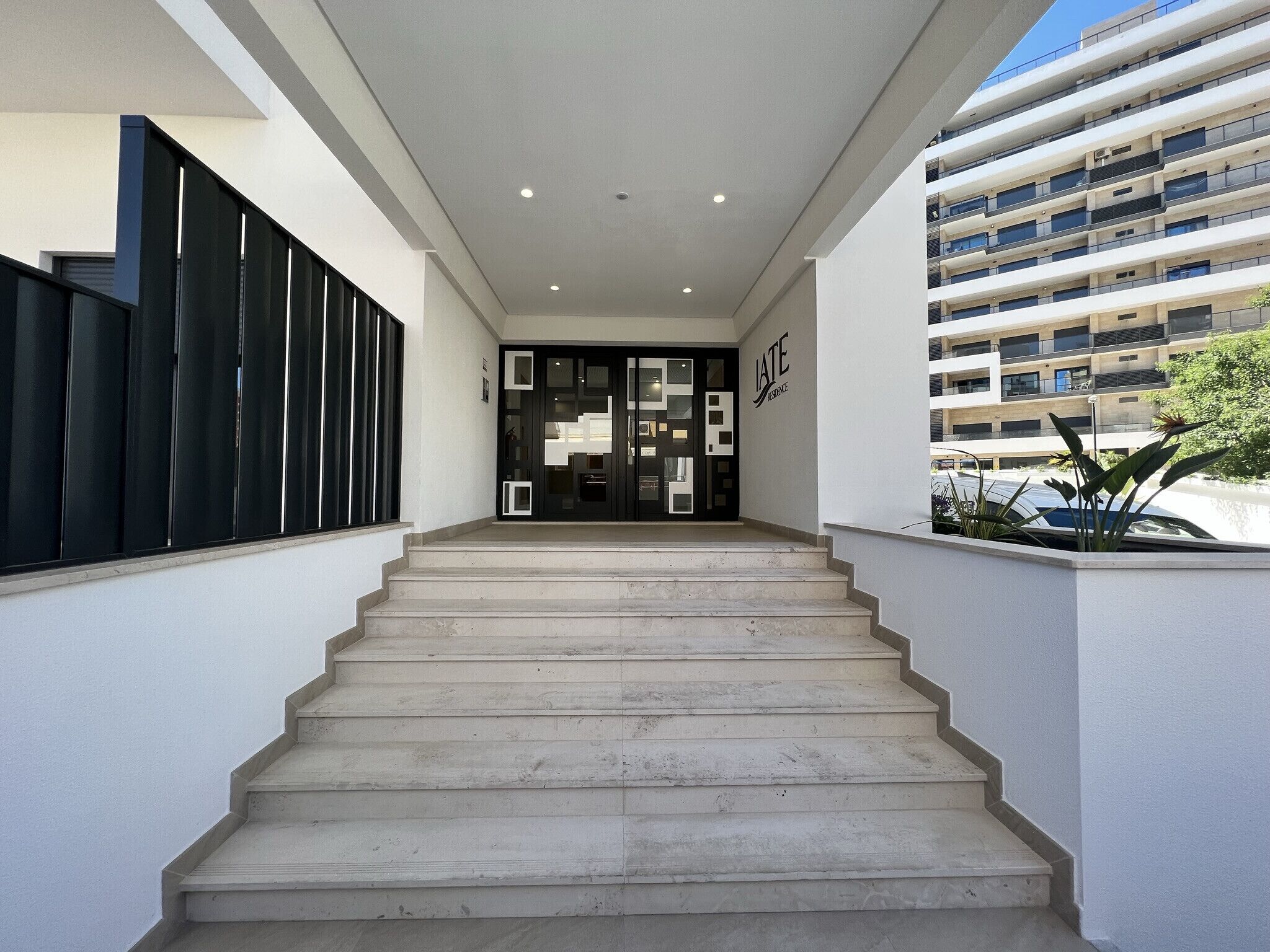 Une entrée moderne, avec un escalier menant à un intérieur sombre.
