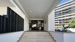 A modern building entrance with a staircase leading to a dark interior. - PRAIA DA ROCHA MODERN by HOMING (Praia da Rocha)