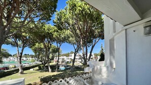 A balcony with a table set for breakfast, overlooking a pool and buildings. - ALBUFEIRA BALAIA GOLF VILAGE 2 WITH POOL by HOMING (Albufeira)