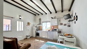 Ein modernes Zimmer mit Bett, einer braunen Ledersofa, einer Küchenzeile und einem Essbereich.