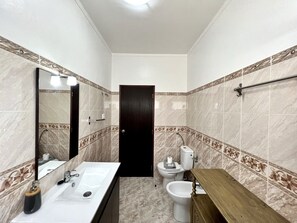 Un baño con lavamanos, espejo, inodoro y bidé.
