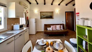Una cocina compacta con comedor, un sofá y una estantería verde.