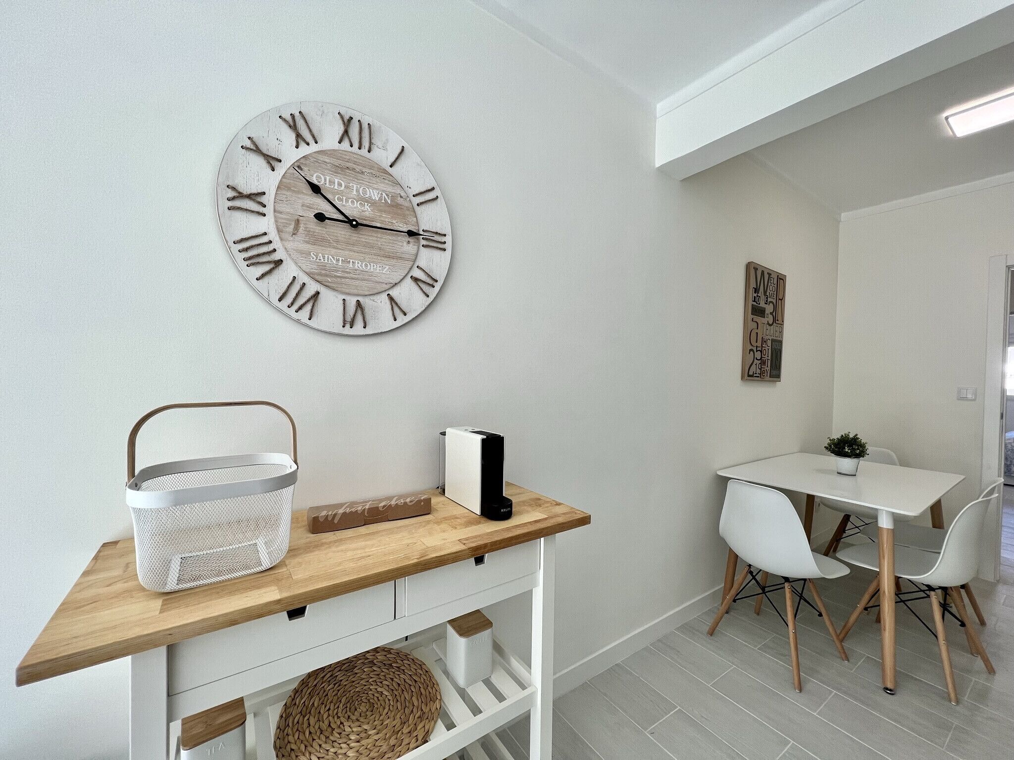 Une cuisine moderne avec un plan de travail en bois, un panier tressé, un panier blanc et une horloge murale.