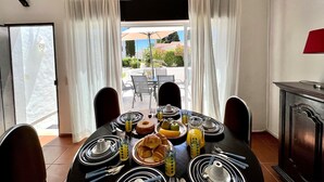 Un coin repas avec une table mise pour le petit-déjeuner, comprenant des croissants, des fruits et du jus.