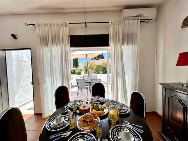A dining area with a table set for breakfast, including croissants, fruit, and juice.