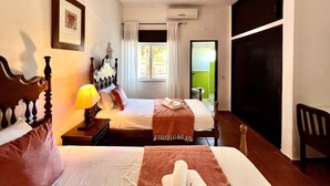 Une chambre d’hôtel avec deux lits, une fenêtre avec des rideaux, un appareil de climatisation et une vue sur l’extérieur.