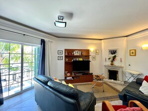 A living room with a sofa, a television, a fireplace, and a bookshelf. - TAVIRA PALM TREE by HOMING (Tavira)