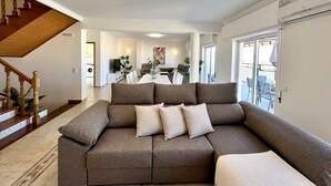 Ein modernes Wohnzimmer mit einer Eckcouch, einem Essbereich und einer Treppe.