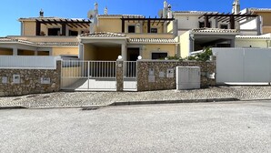 Un edificio residenziale a più piani con facciata in pietra, ingresso carrabile e cielo azzurro.