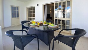A dining area with a round table and four chairs, a door, and a window with curtains. - VILAMOURA GARDEN VIEW 2 WITH POOL by HOMING (Vilamoura)