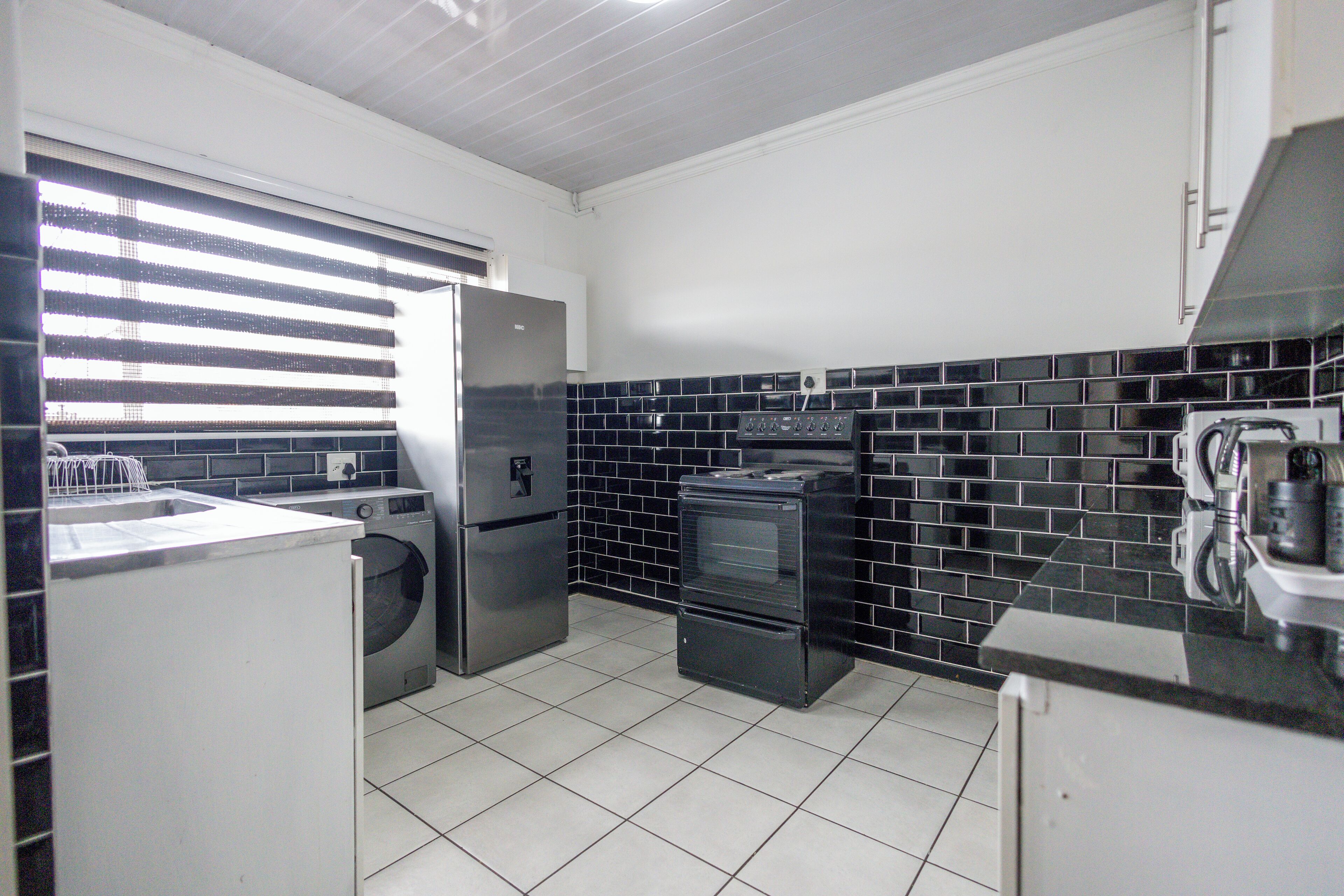 A compact kitchen with a washing machine, a refrigerator, an oven, and a microwave.