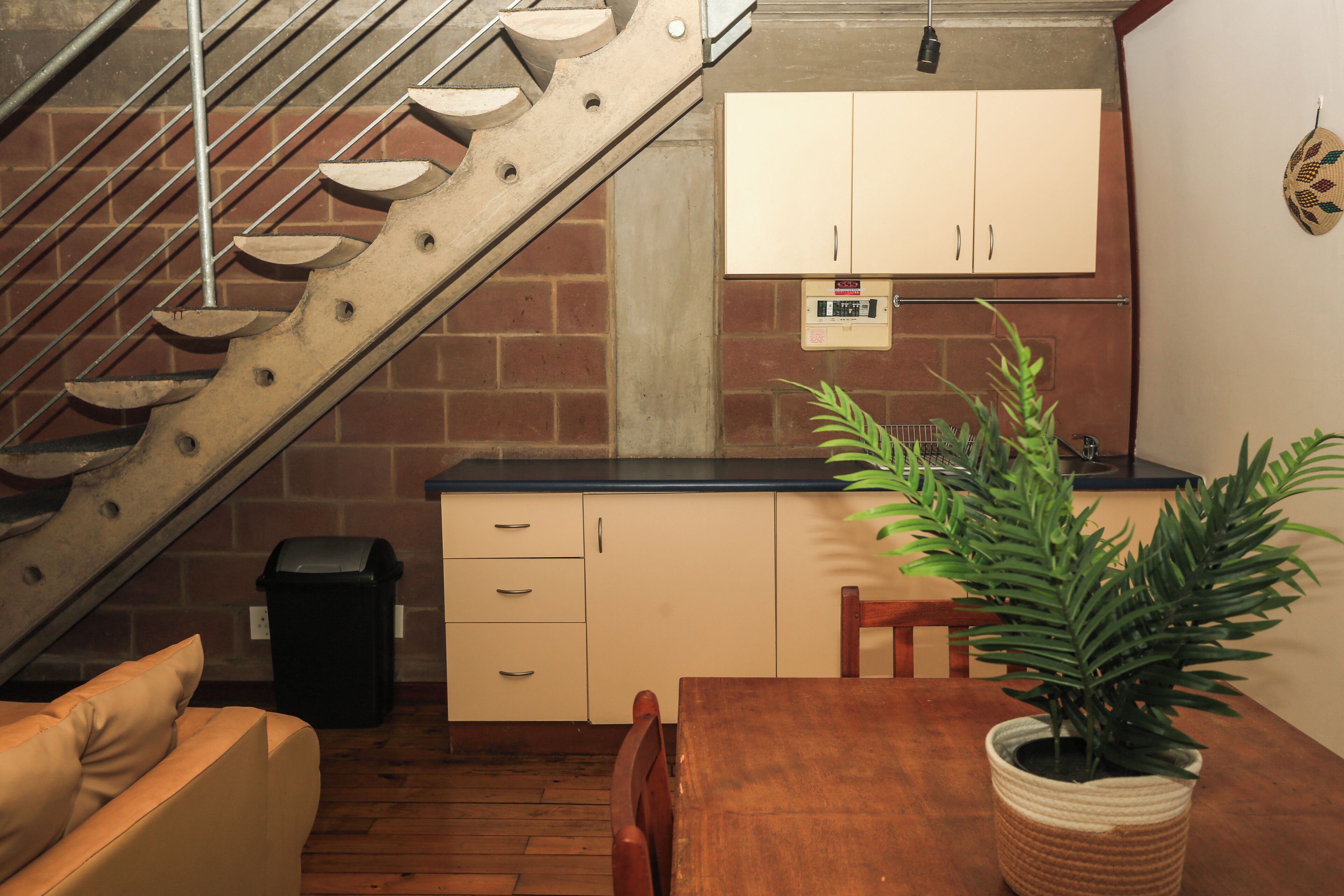 Una cocina con una mesa de madera, una planta en maceta y una escalera.