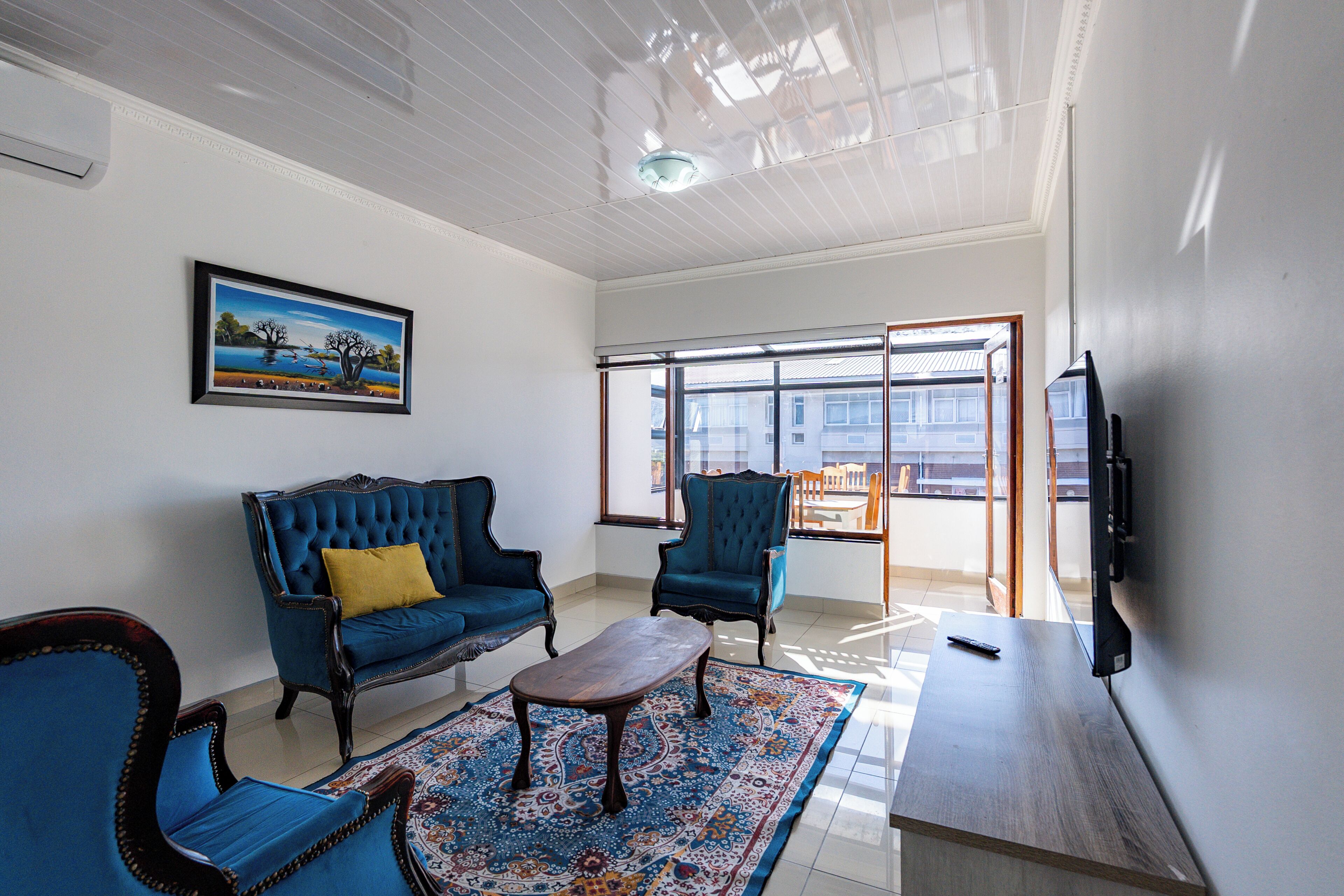 A living room with a blue sofa, matching armchair, a coffee table, and a TV on a stand.