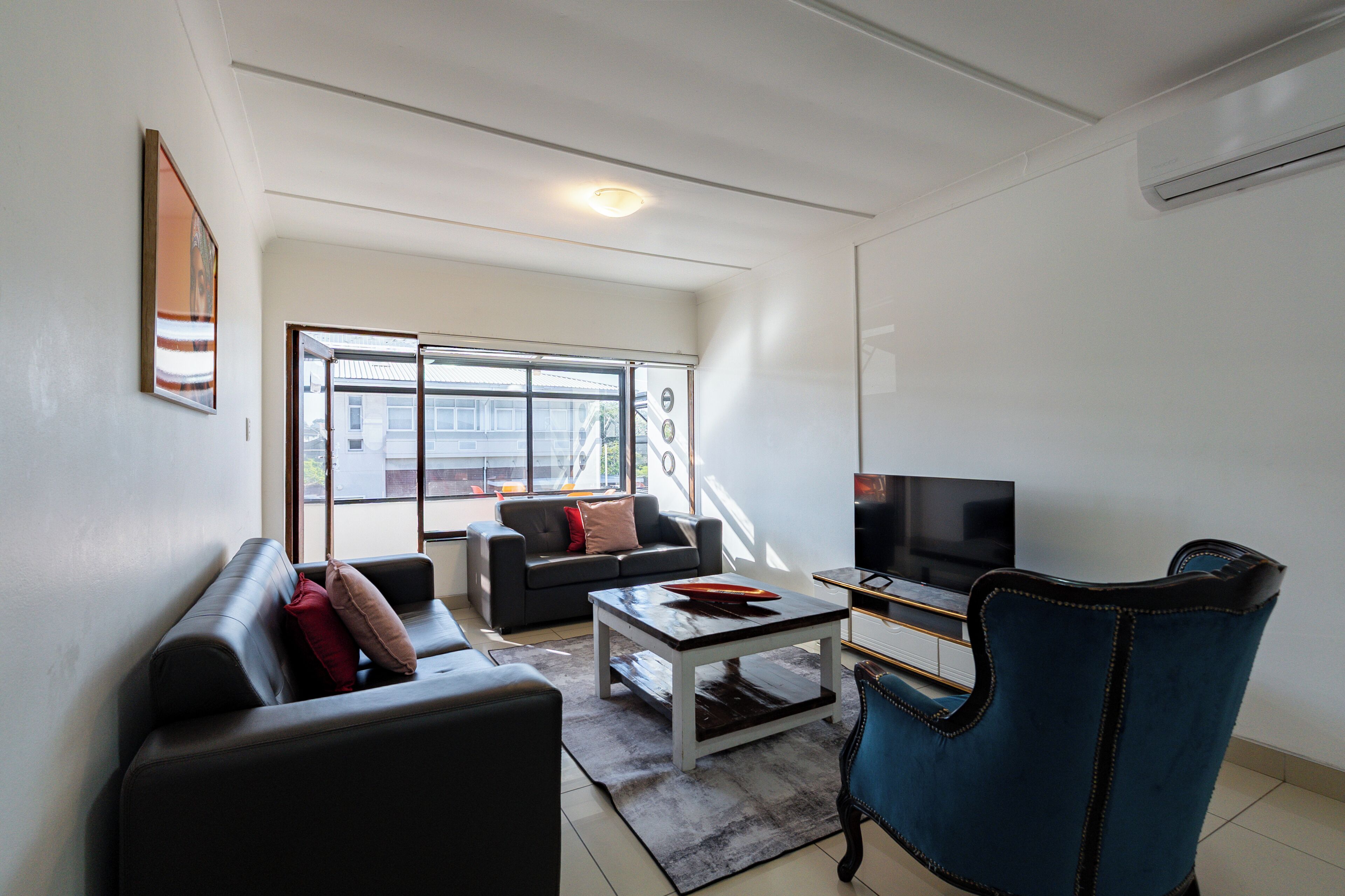 Een woonkamer met een bank, een salontafel, een televisie en een fauteuil.