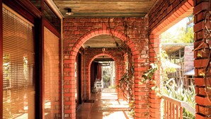 A brick corridor with arched ceilings, a tiled floor, and a metal railing on one side. - Safi Self-Catering Suites (East London)