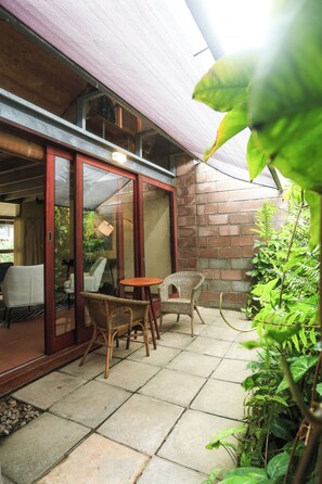 A patio area with wicker furniture, a small round table, and a glass door leading to a room.