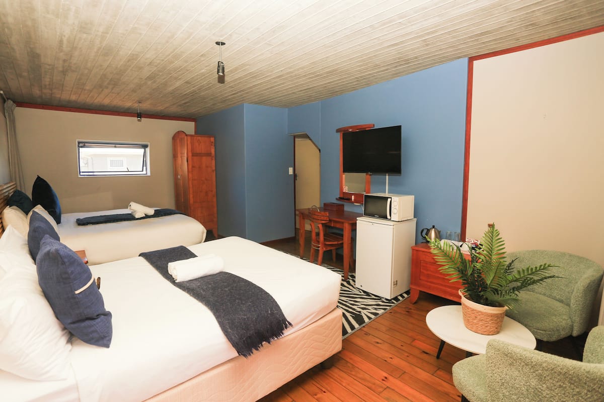 Una habitación de hotel con cama, escritorio, televisión y una planta.