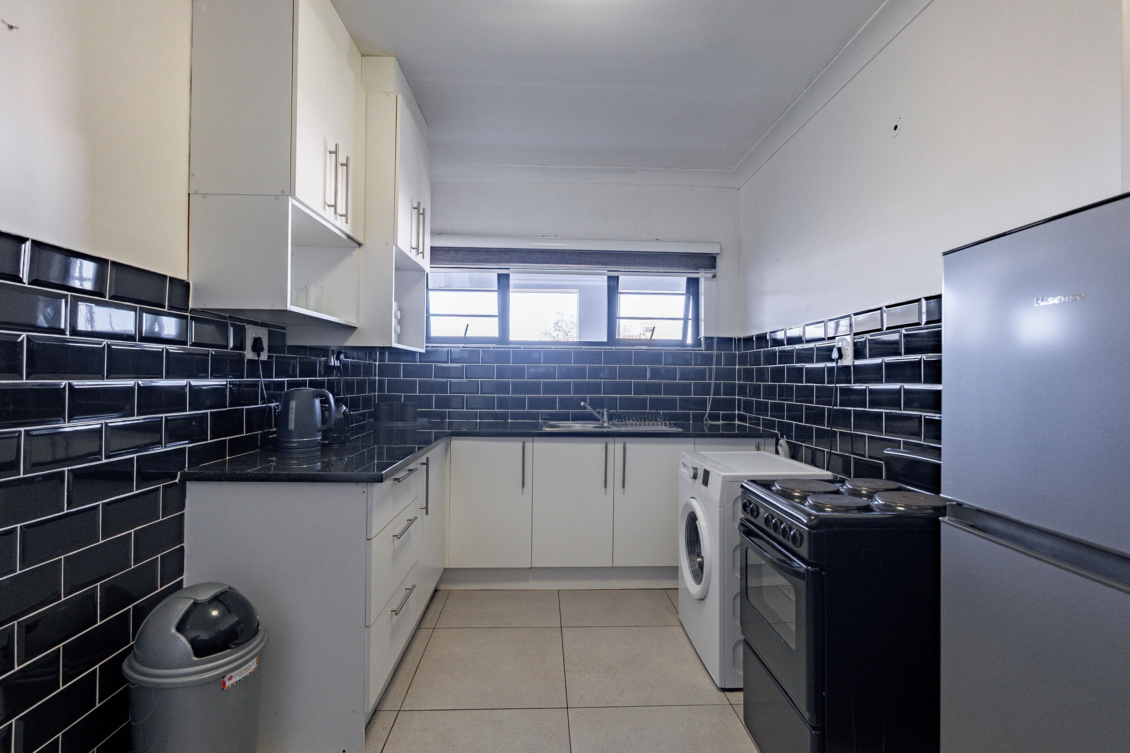 A compact kitchen with a washing machine, a stove, and a refrigerator.