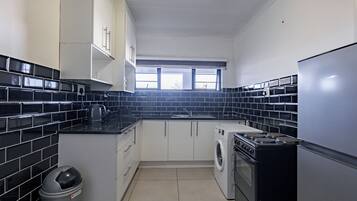 A compact kitchen with a washing machine, a stove, and a refrigerator.