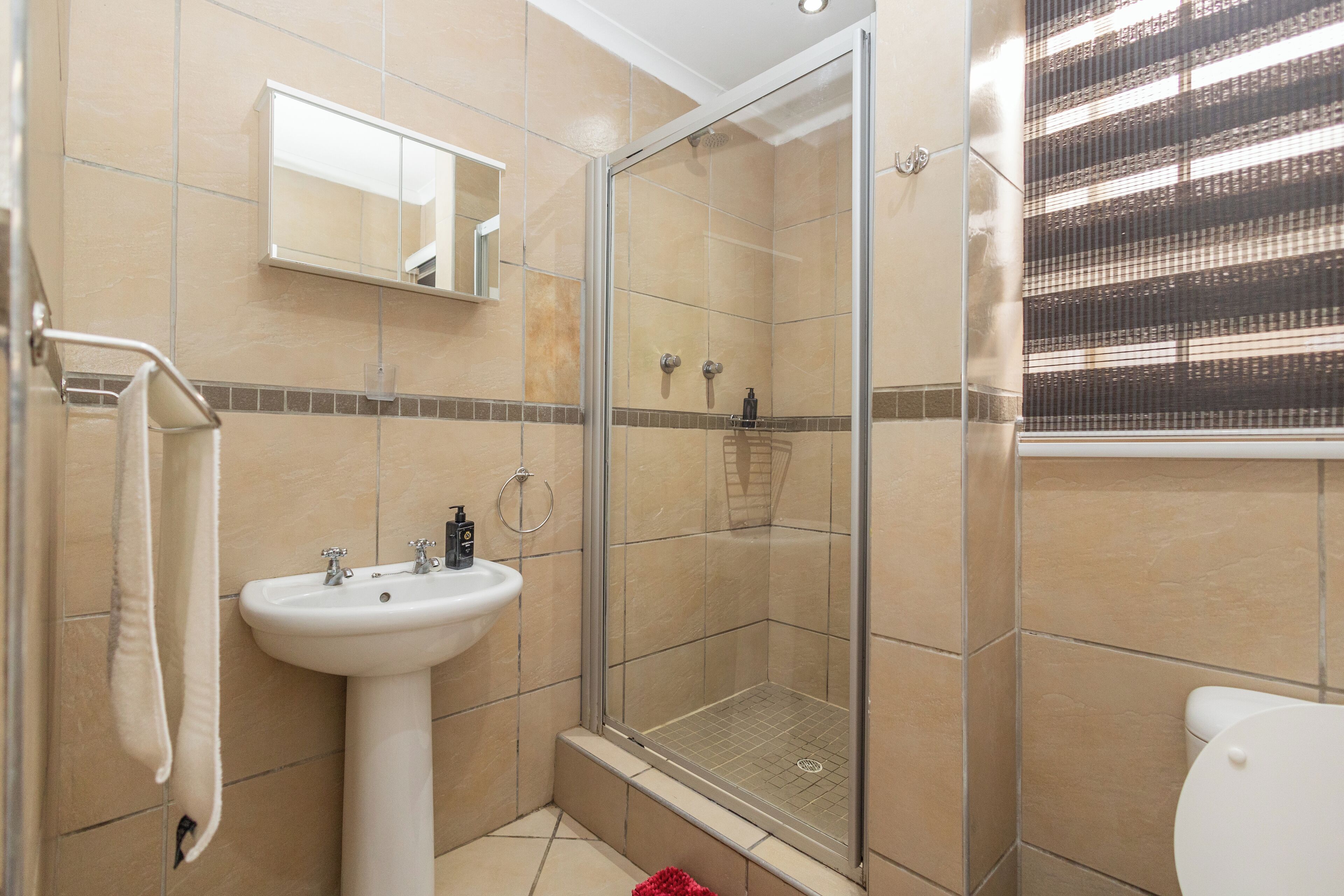 A bathroom with a glass-enclosed shower, a sink, and a toilet.