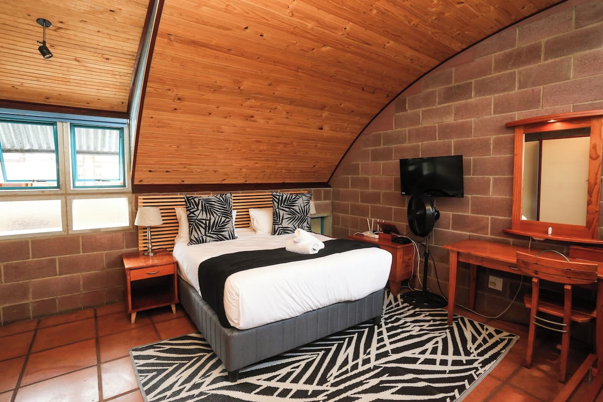 Un dormitorio con cama, televisor, escritorio y espejo.