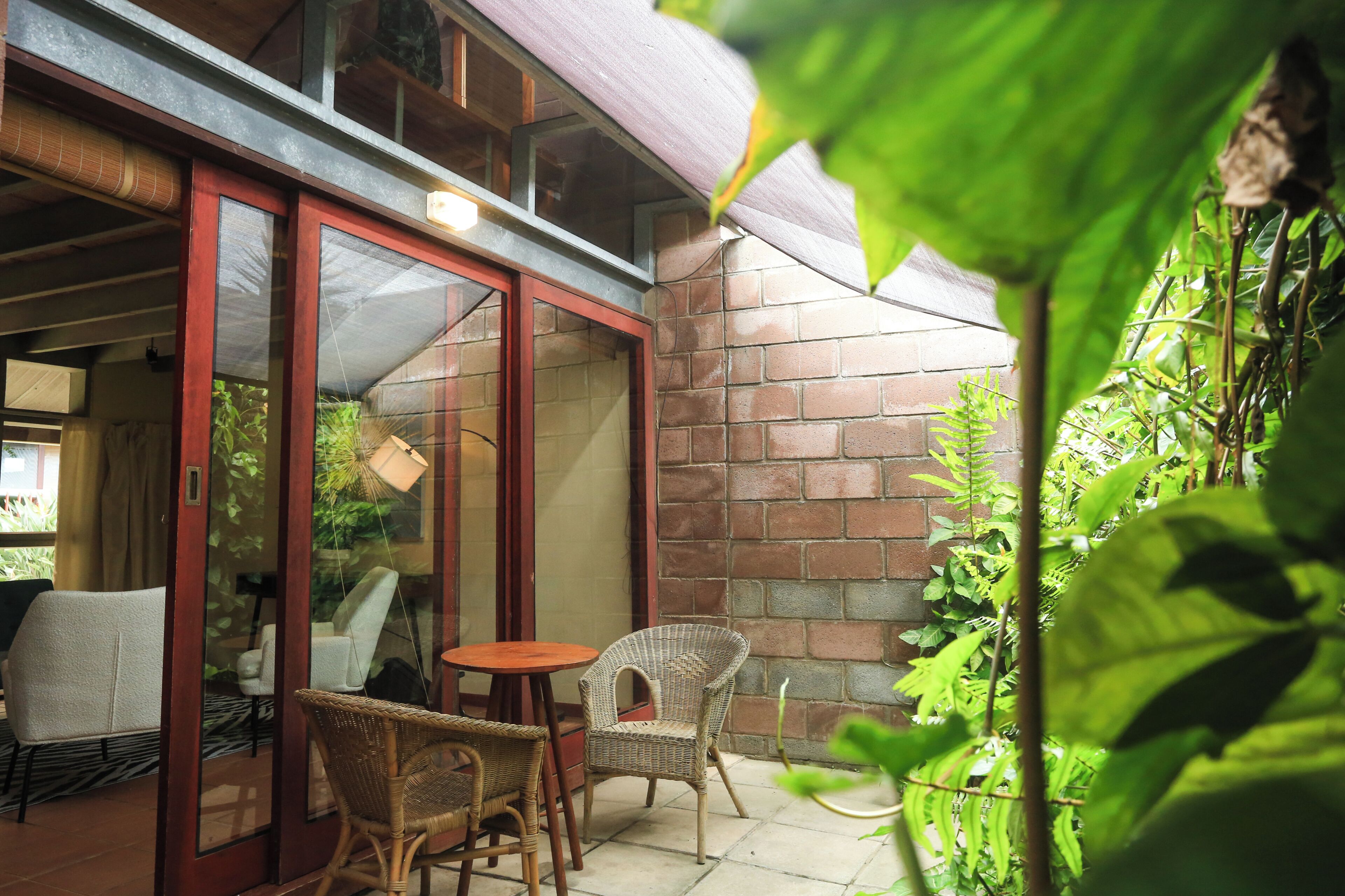 A patio with wicker chairs, a small round table, and a glass door leading to an interior space.