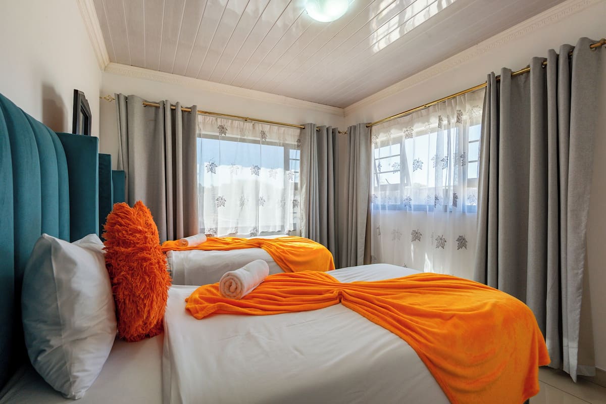 Habitación de hotel con dos camas, un ventanal con cortinas y una lámpara en el techo.