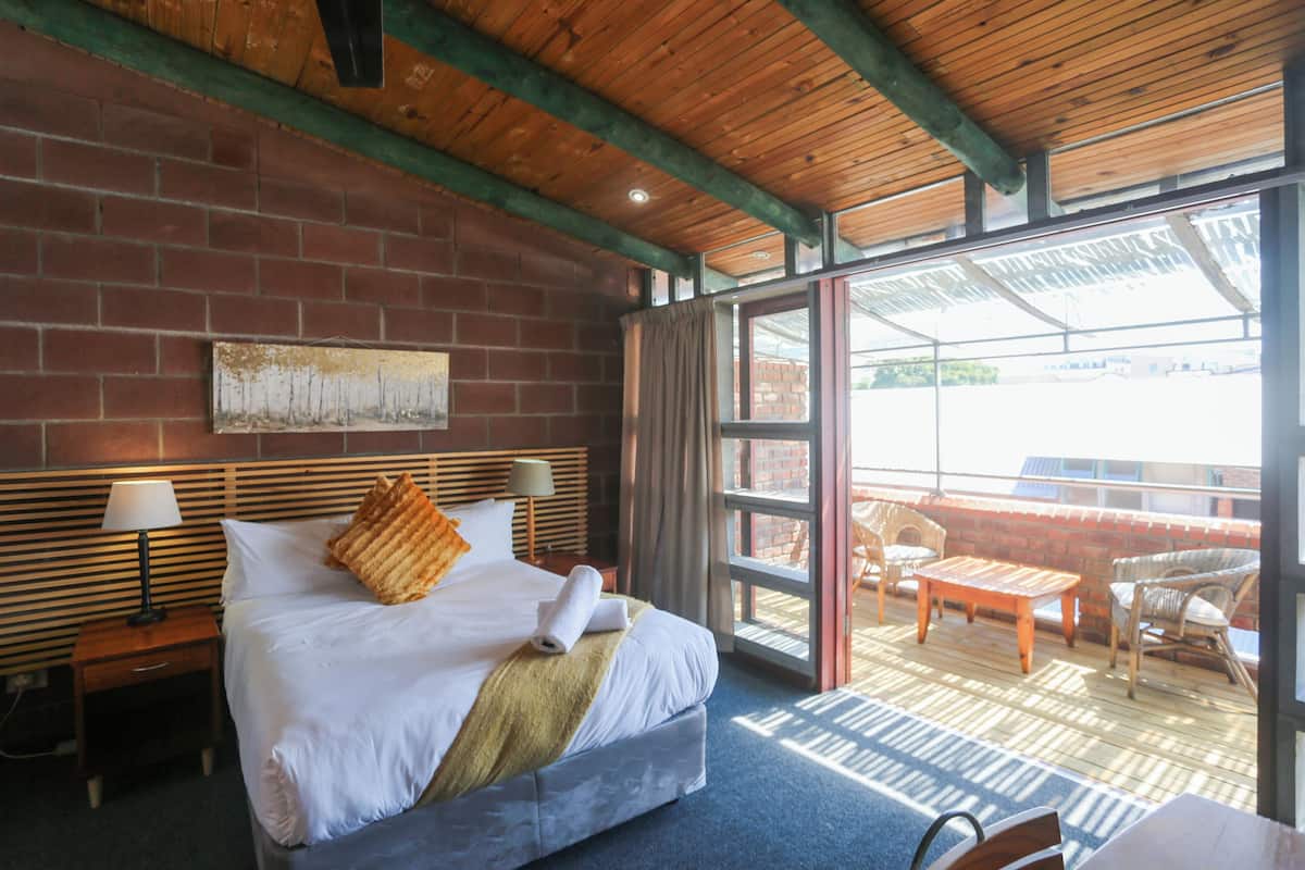 Habitación de hotel con cama, mesita de noche, ventana y vistas al exterior.