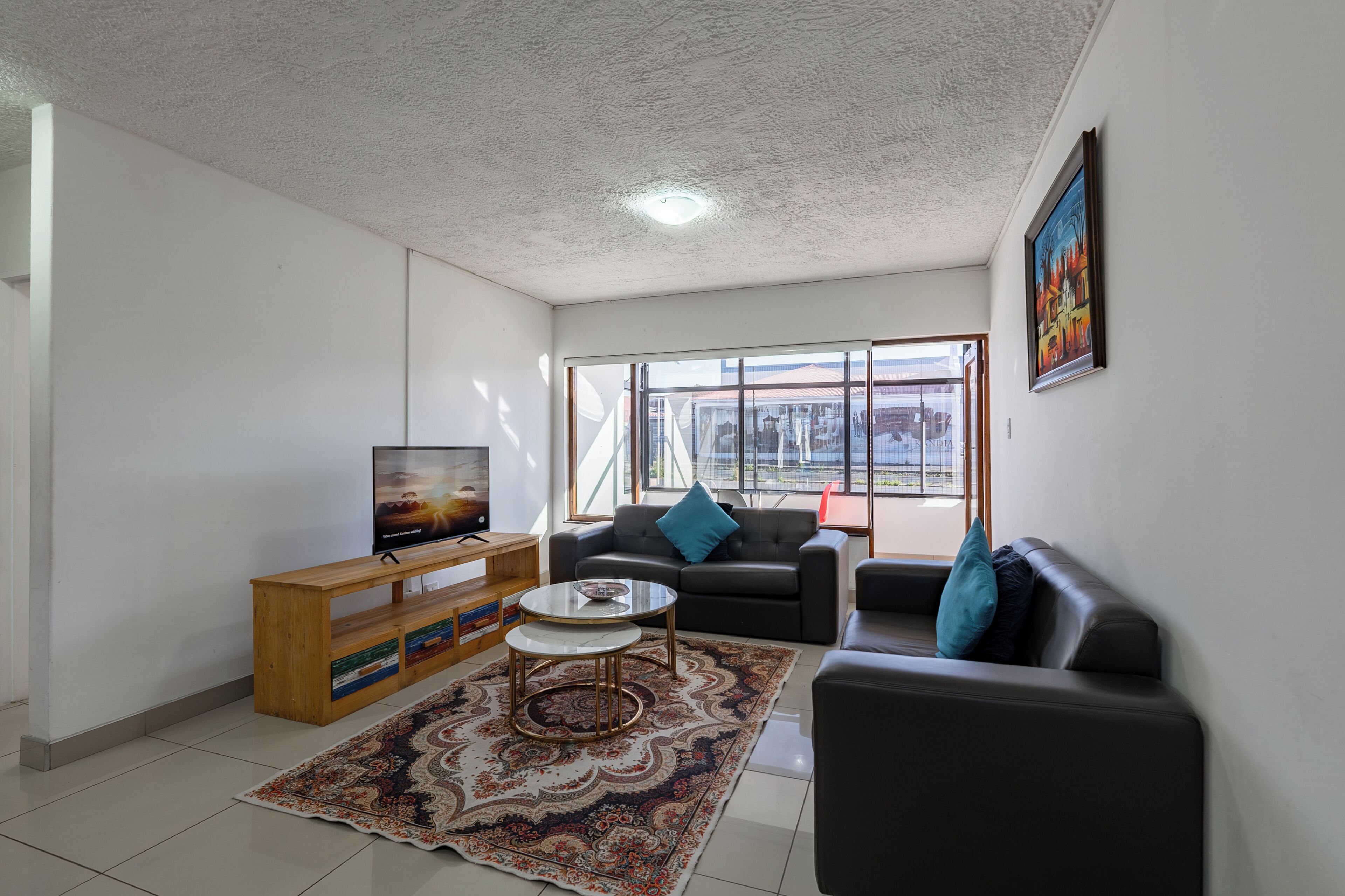 A living room with a TV, sofa, coffee table, and a patterned rug.