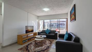 A living room with a TV, sofa, coffee table, and a patterned rug.