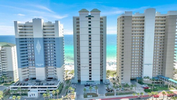 A high-rise hotel with multiple floors, a parking area, and a beach view. - Ocean Ritz 2 Primary Suites | Expansive Balcony | Sleeps 12 (Panama City Beach)