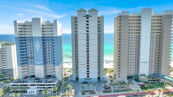 Un hôtel de grande hauteur, avec de nombreux étages, un parking et une vue sur la plage.