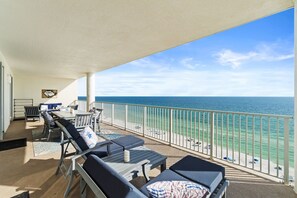 A balcony with a view of the ocean, furnished with lounge chairs and a table. - Ocean Ritz 2 Primary Suites | Expansive Balcony | Sleeps 12 (Panama City Beach)