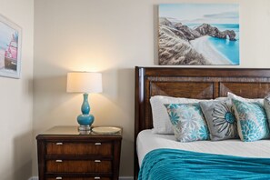 A bedroom with a wooden headboard, a bedside table with a lamp, and a bed with patterned pillows. - Ocean Ritz 2 Primary Suites | Expansive Balcony | Sleeps 12 (Panama City Beach)