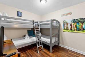 A bunk bed room with a ladder, a painting of surfboards, and a 'BEACH' sign on the wall.