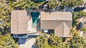 Vue aérienne d’une propriété résidentielle dotée d’une piscine, d’un patio couvert et d’une cour clôturée.