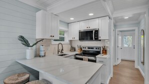 Une cuisine moderne avec des meubles blancs, un grand îlot central et un four à micro-ondes.
