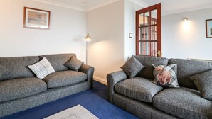 A living room with two grey sofas, a blue carpet, and a floor lamp. - Shoreline House (Fraserburgh)